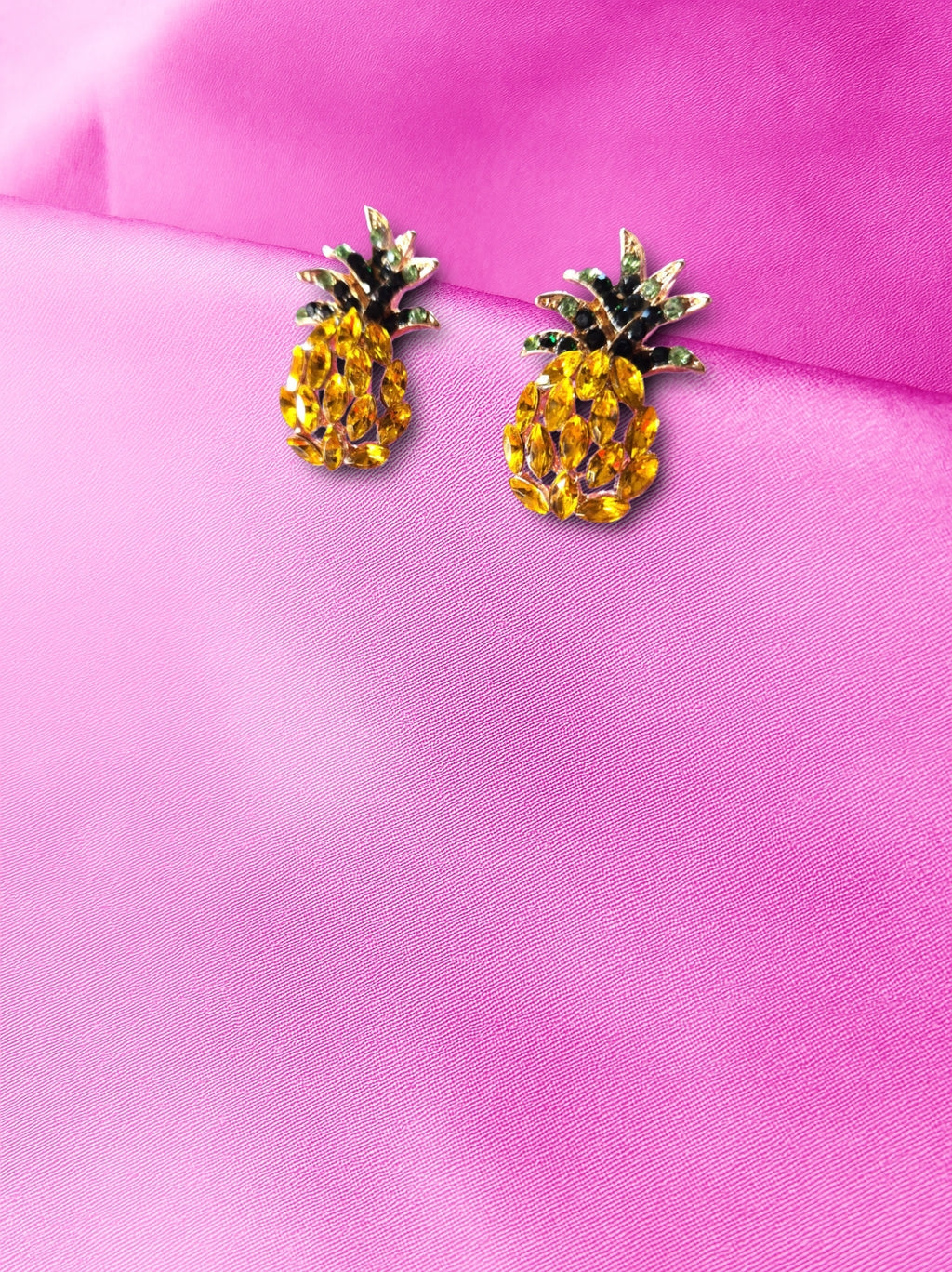 Pineapple shaped earrings on a pink background