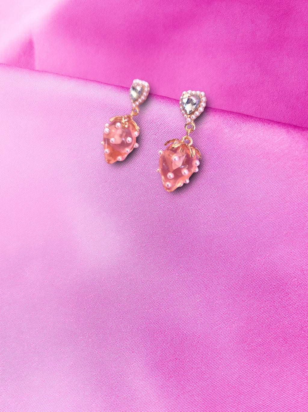Pink earrings with gold and silvers accents on a pink satin background