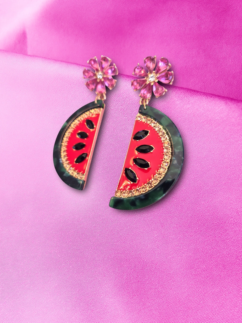 Watermelon slice earrings on a pink fabric background
