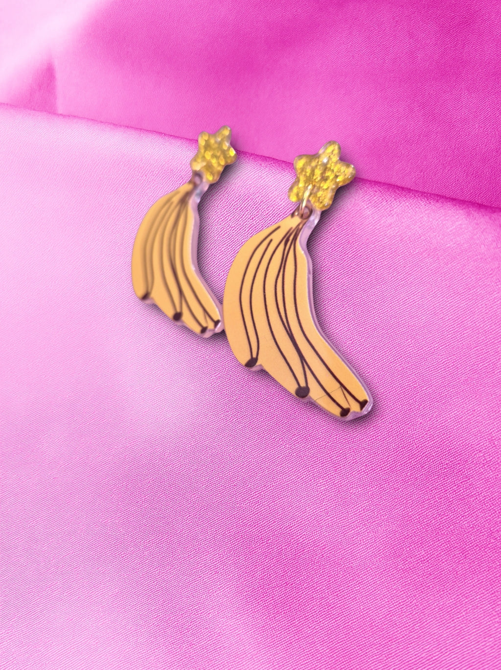 Banana-shaped earrings on a pink background