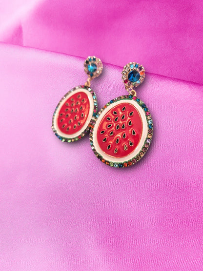 Watermelon-themed earrings with gemstones on a pink background