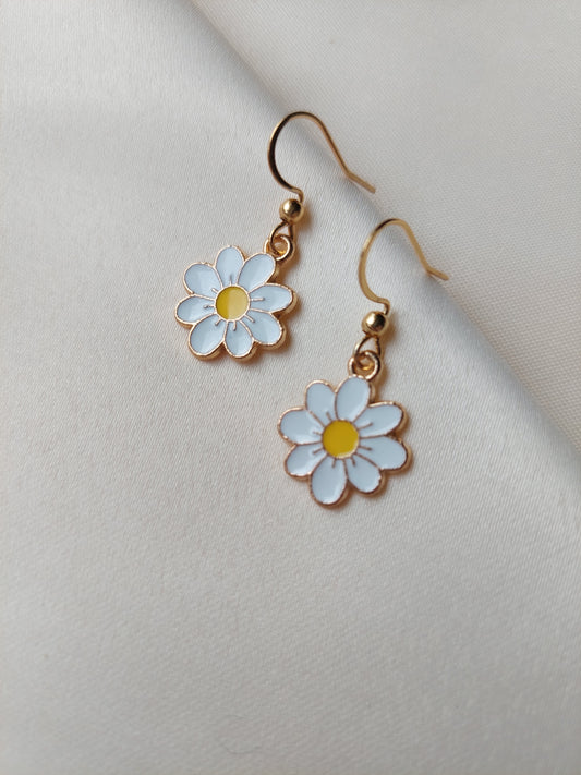 White petal flower earrings with yellow centre. Gold trim around outside of flower. Gold Hooks. Earrings laid on fabric. 