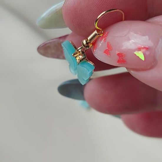Blue butterfly earrings with gold body. Gold hooks. Hand shown to scale. 