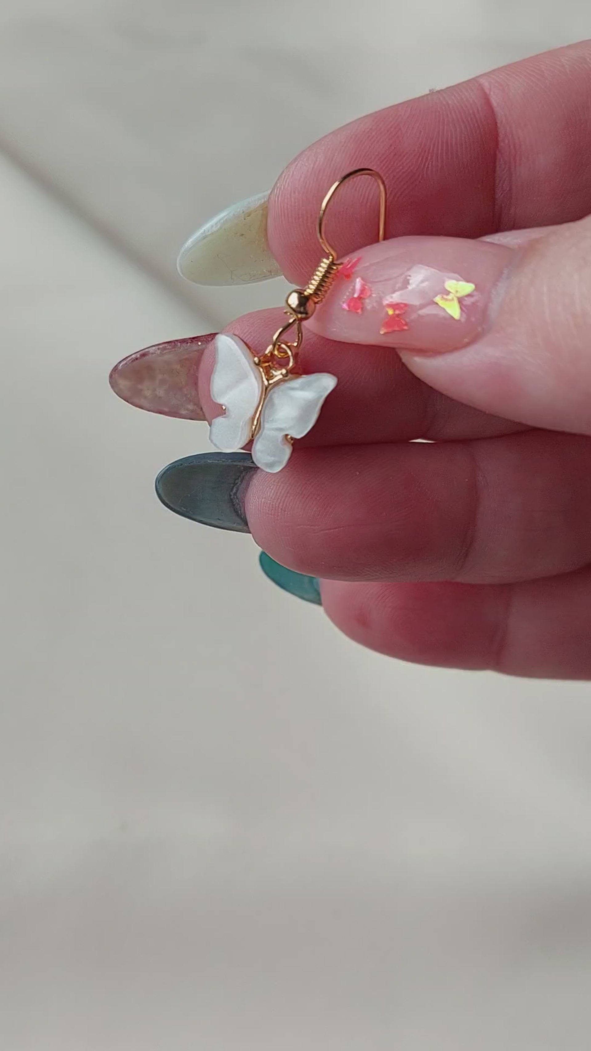 White butterfly earrings with gold body. Gold hooks. Hand shown to scale. 