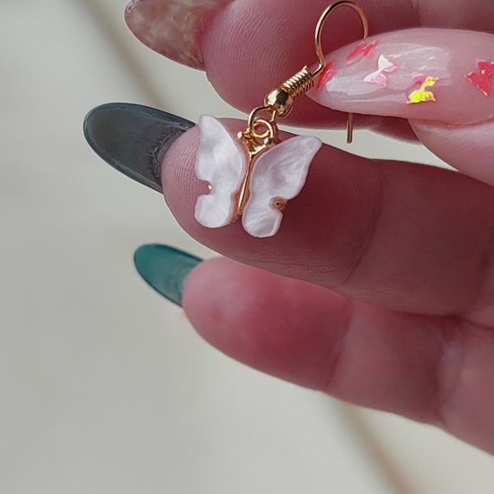Pink butterfly earrings with gold body. Gold hooks. Hand shown to scale. 